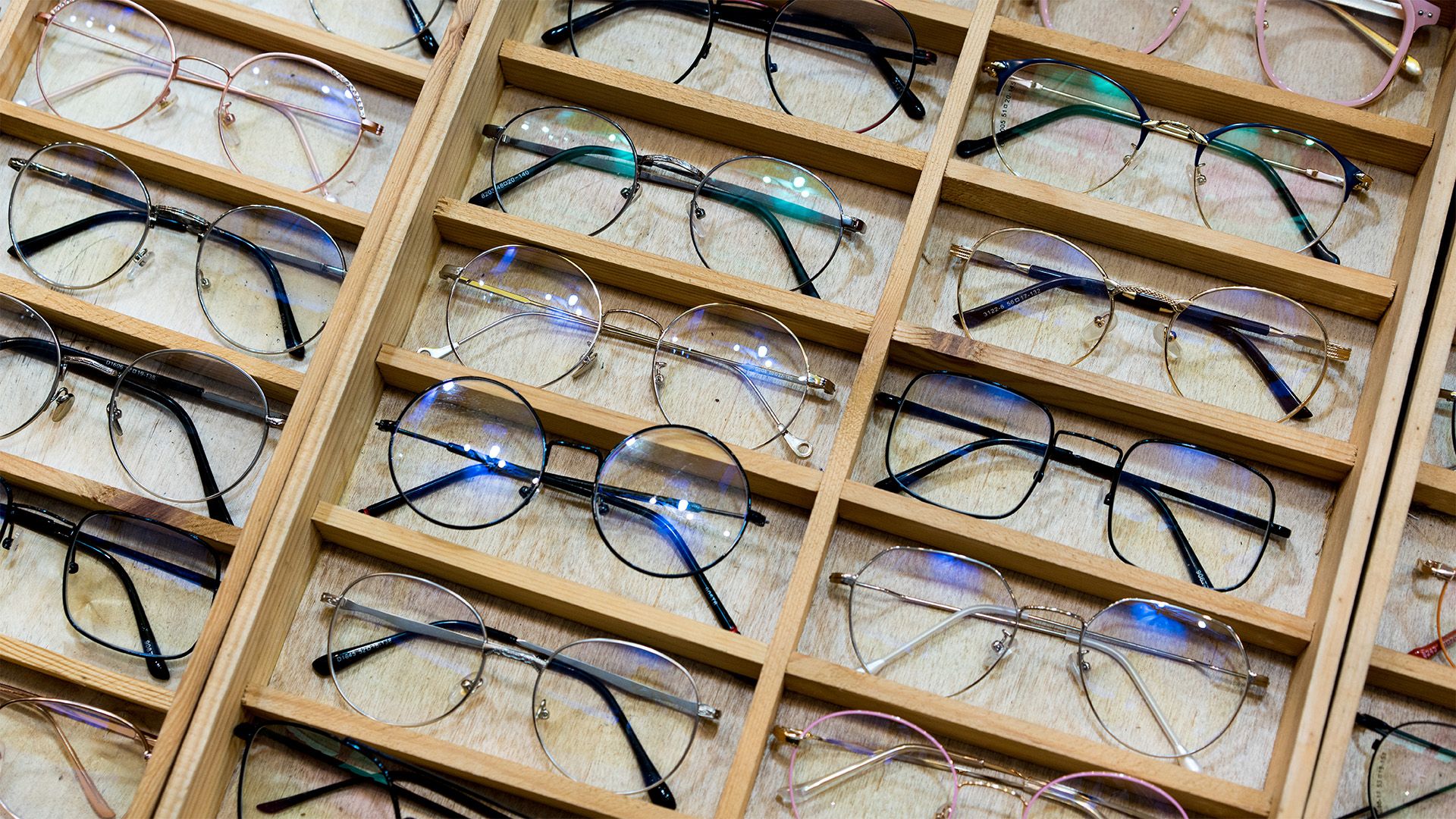Auswahl moderner Brillenfassungen in einem Optikgeschäft, verschiedene Modelle und Farben in Holzdisplay